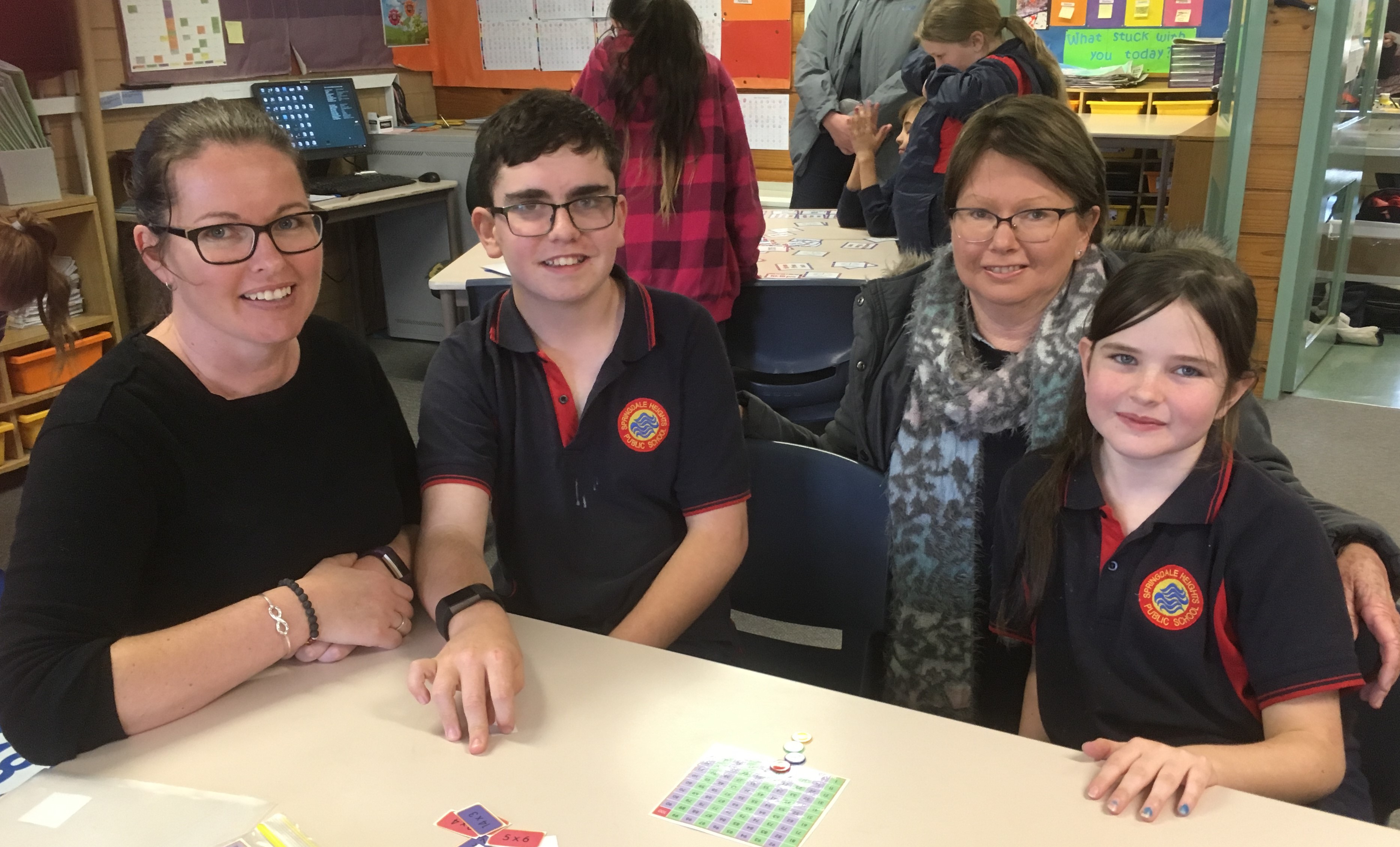 Parents sitting with students at a desk